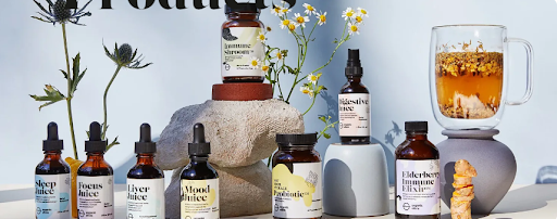 Assortment of herbal tincture and wellness bottles displayed with flowers and tea, representing natural health and holistic remedies.